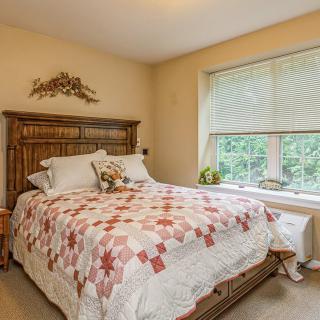 A cozy bedroom with a quilt-covered bed and large window.