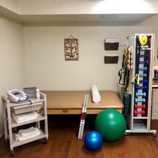 A well-equipped physical therapy room featuring a treatment table, exercise balls, and various medical devices.