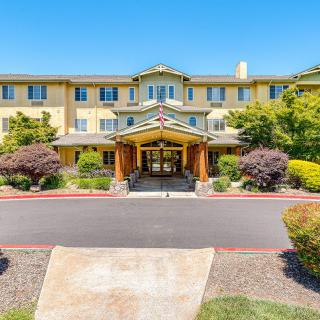 A hotel entrance with well-maintained landscaping and a clear blue sky.