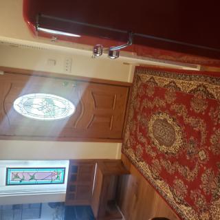 A warmly lit entrance with a decorative carpet and stained glass window.