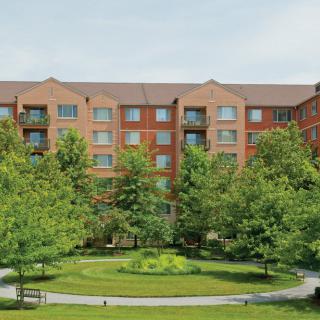 A residential apartment building surrounded by well-maintained landscaping and trees.