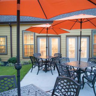An inviting outdoor patio area featuring tables with orange umbrellas, perfect for evening gatherings.