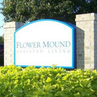 A sign at the entrance of Flower Mound surrounded by lush greenery.
