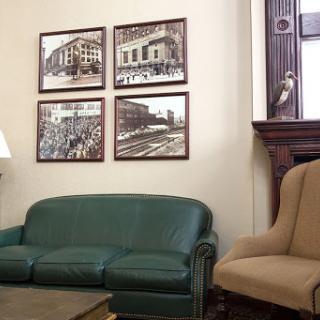 A cozy living room featuring a green sofa, beige armchair, and framed photographs on the wall.