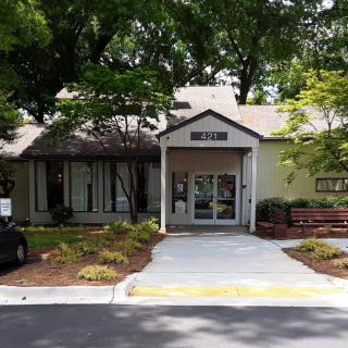 Entrance to a building surrounded by trees and landscaping.