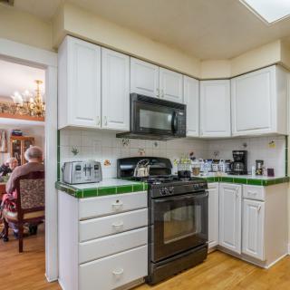A modern kitchen with white cabinets and green tile backsplash.