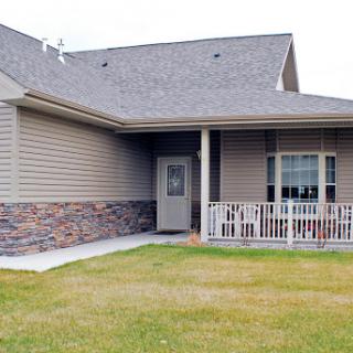 A charming single-story house with a cozy porch and well-maintained lawn.