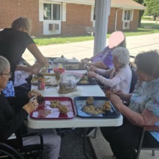 A group of elderly people enjoying a meal together outdoors.