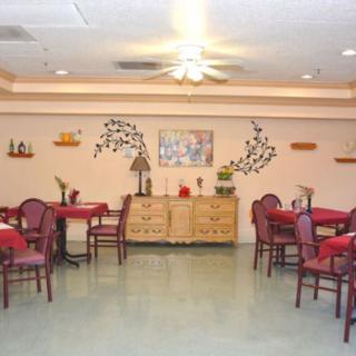A cozy dining room with neatly arranged tables and chairs, decorated walls, and soft lighting.