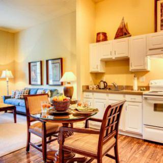 A cozy living space featuring a kitchen, dining table, and sofa in a warmly lit setting.