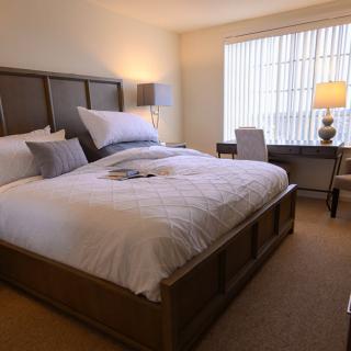 A cozy bedroom with a large bed, a desk, and soft lighting.