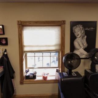 A cozy barber shop interior featuring a window, wall art, and hair dryers.