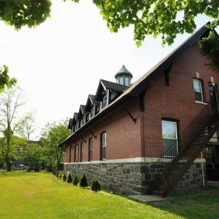 A red brick building surrounded by lush greenery and trees under a clear sky.