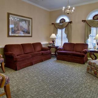 A traditional living room with two brown sofas, a patterned carpet, and a chandelier.