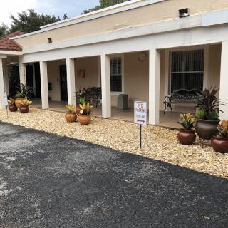 A building with a columned porch and decorative plants lining the entrance.