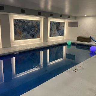 A modern indoor swimming pool with colorful lighting and wall art.