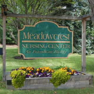 A sign for Meadowcrest Nursing Center surrounded by a landscaped garden with colorful flowers.