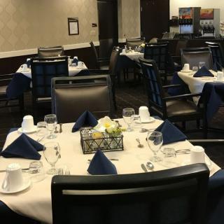 Elegantly set tables in a restaurant dining area, featuring white tablecloths and navy blue napkins.