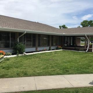 A view of a well-maintained residential building with a green lawn and sidewalk.