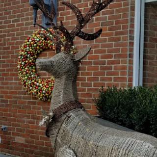 A beautifully crafted deer sculpture adorned with a festive wreath.