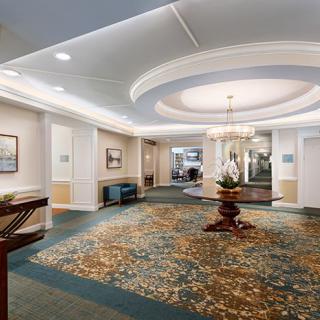 A spacious and elegantly designed lobby featuring a chandelier and decorative plants.