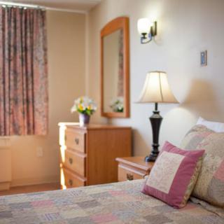 A cozy bedroom with a neatly arranged bed, elegant lamp, and floral curtains.