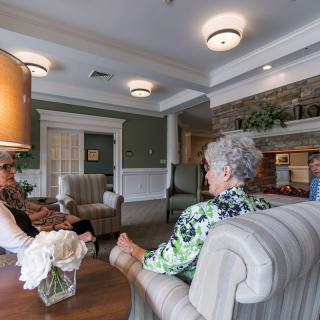 A group of people sitting and conversing in a comfortable lobby area.