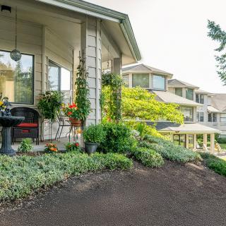 A beautiful house with a lush garden and cozy porch area.