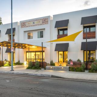 A modern building with prominent awnings and a well-lit entrance, viewed from the street.