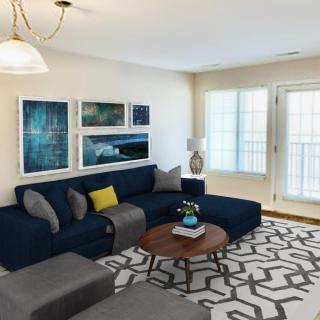 A modern living room with a navy sofa, abstract artwork, and geometric patterned rug.