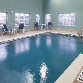 An indoor swimming pool area with tables and chairs by the windows.