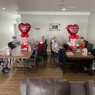 A group of people celebrating Valentine's Day with heart-shaped balloons and decorations.