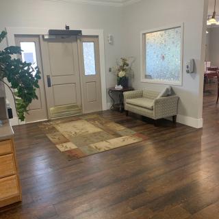 A cozy lobby area featuring a comfortable sofa, a potted plant, and wooden flooring.