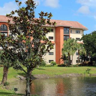 A scenic view of an apartment building surrounded by trees and a lake.