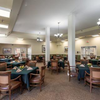 A spacious dining area featuring multiple tables and chairs, with elegant lighting and tasteful decor.