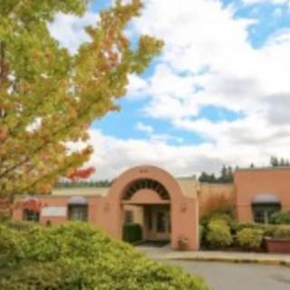 A building with an arched entrance surrounded by trees and a cloudy sky.