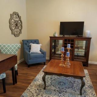 A cozy living room with a blue armchair, wooden coffee table, and a cabinet with a television.