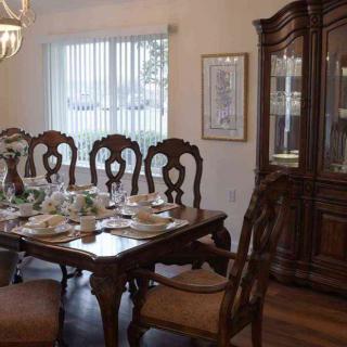 An elegantly set dining room with a classic wooden table and chairs, adorned with fine dinnerware and a china cabinet.