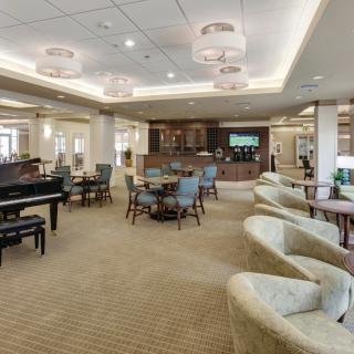 A spacious and elegantly designed lounge area with comfortable seating, a piano, and a television.