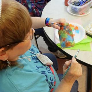 A child engaged in a crafting activity, painting a colorful design on a piece of material.