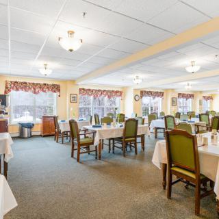A spacious dining room with neatly arranged tables and chairs, featuring elegant decor and ample natural light.
