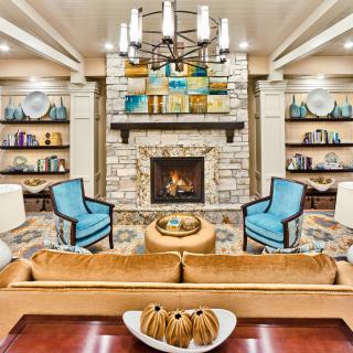 A cozy living room with a stone fireplace, surrounded by bookshelves and elegant furniture.