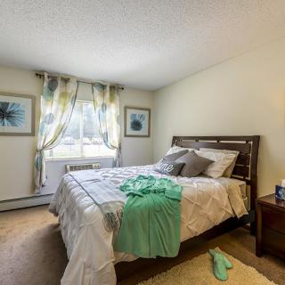 A cozy bedroom with a neatly made bed, colorful curtains, and tasteful decor.