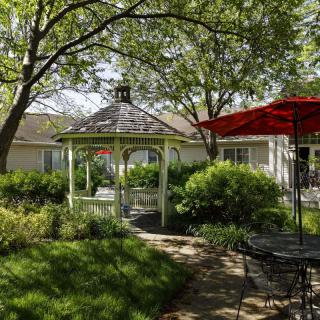 A peaceful garden with a gazebo, surrounded by lush greenery and outdoor seating.