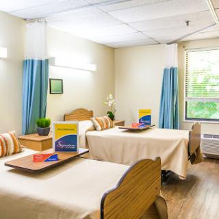 A welcoming hospital room designed for patient comfort with two beds and simplified amenities.