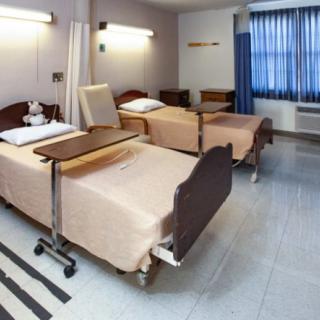 A hospital room with two beds and medical equipment.