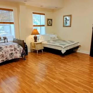 A cozy and spacious bedroom featuring two beds, warm wooden flooring, and ample natural light.