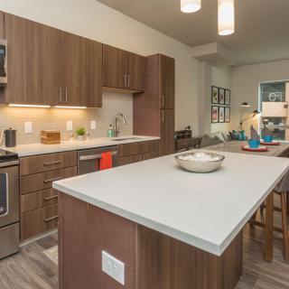 A modern kitchen featuring wood cabinets, a large island, and stainless steel appliances.