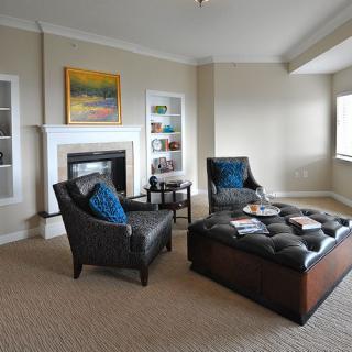 A modern living room featuring comfortable seating, a fireplace, and decorative artworks.