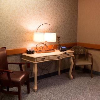 A quiet waiting room corner with a desk, two chairs, and a decorative lamp.